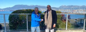 two men shake hands on a balcony overlooking the water.