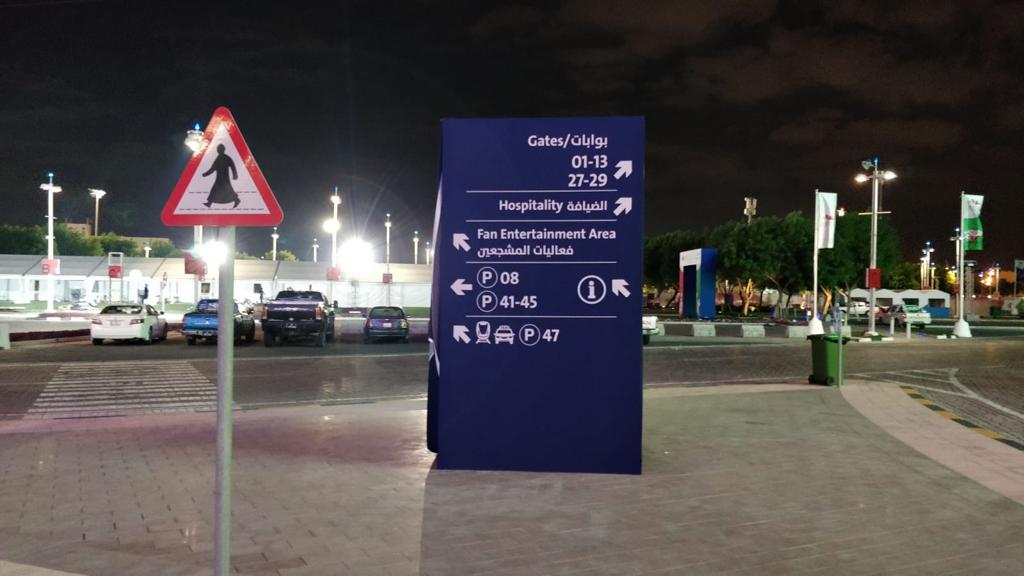 a blue sign in the middle of a parking lot at night.